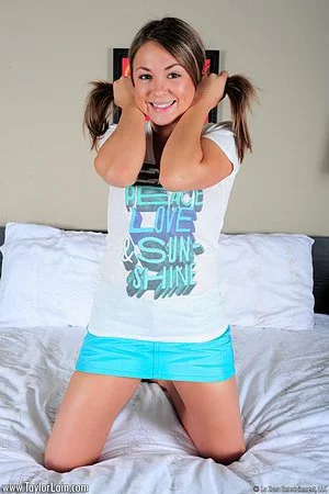 Cute blonde babe Taylor Lain plays in her bed baring her mini skirt and blue panty