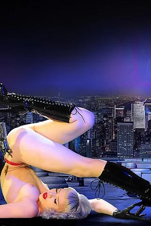 Blonde haired fetish model Mosh dressed in red and black shows her pierced tits