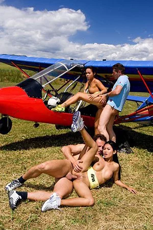 Asian girls Priva and Jade Sin get fucked by two guys in the field beside the plane